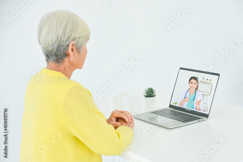 Senior woman sitting in front of laptop computer making video call chat with doctor. Telemedicine concept.