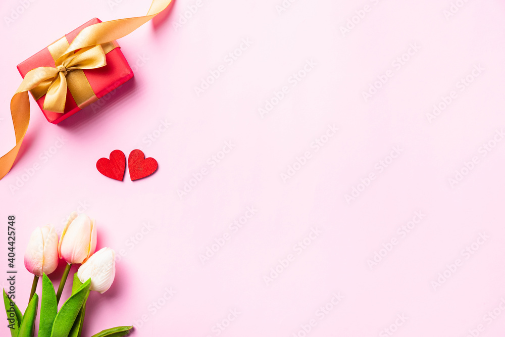 Happy Valentine's day composition background concept. Red gift box with a golden bow ribbon and wood red hearts for love isolated on pink background with copy space. Top View from above