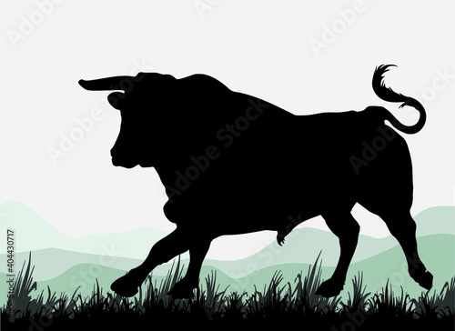 silhouette of a running metal bull, against the background of mountains and sky, for decoration