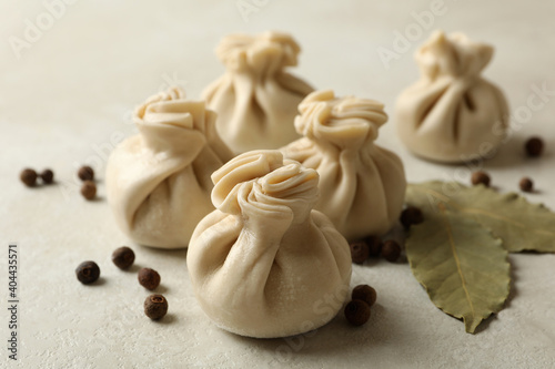 Raw khinkali, pepper and bay leaves on white textured background