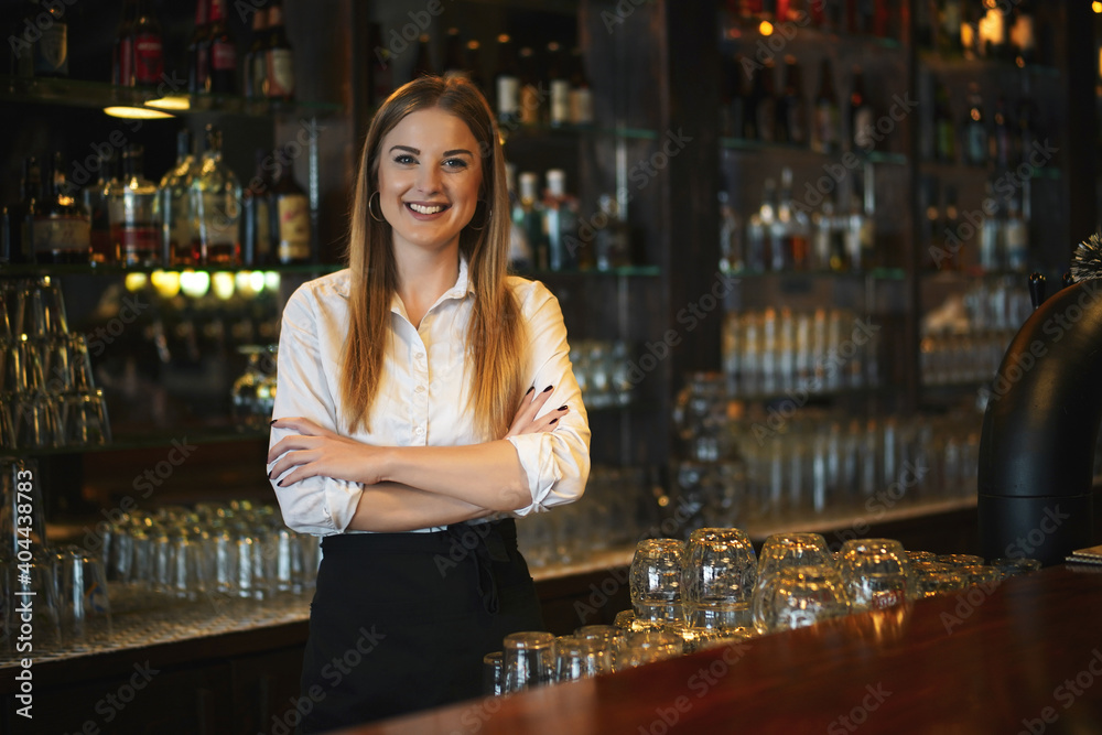 Portrait of happy woman who works as a bartender at bar.