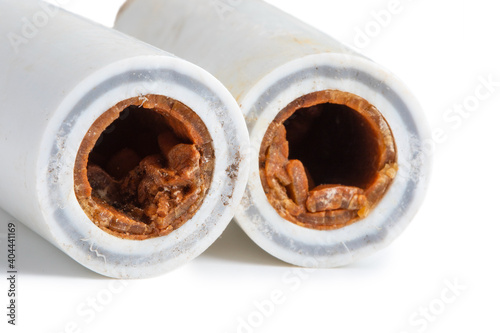 Old broken sludge plumbing polypropylene pipes with red rust and limescale. Corrosion, sludge and hard water concept. Obsolete pipes isolated on white background photo