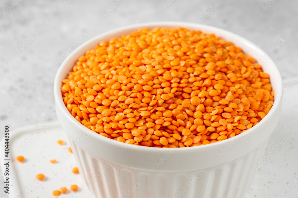 Red lentils in a white bowl on a light gray kitchen table Red lentils in a white bowl on a light gray kitchen table