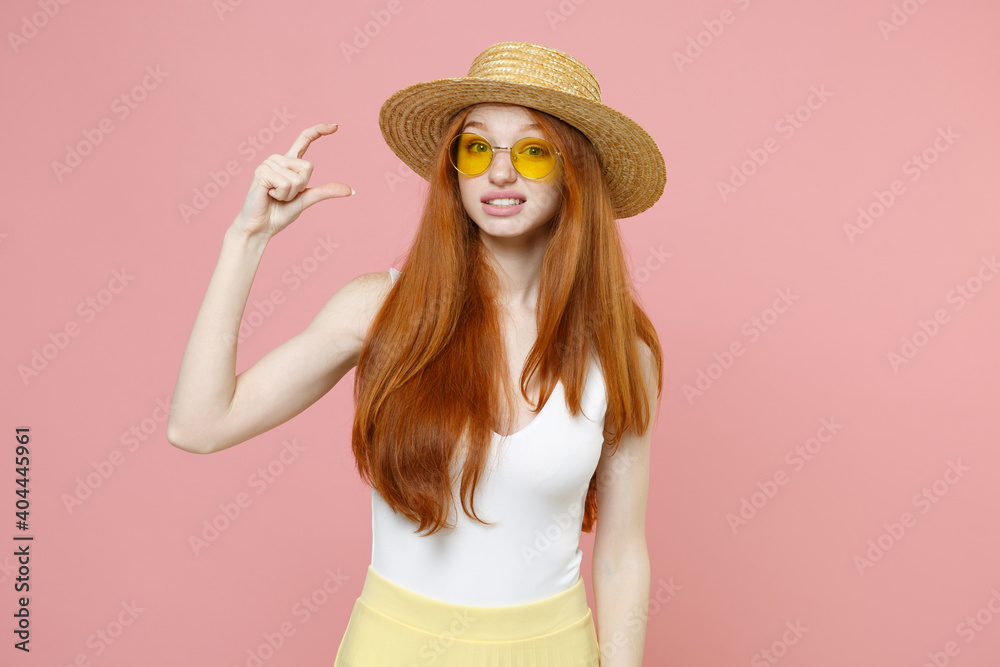 Young redhead cute displeased caucasian woman 20s ginger long hair wear straw hat glasses summer clothes gesturing demonstrating size with workspace isolated on pastel pink background studio portrait. Young redhead cute displeased caucasian woman 20s ginger long hair wear straw hat glasses summer clothes gesturing demonstrating size with workspace isolated on pastel pink background studio portrait.