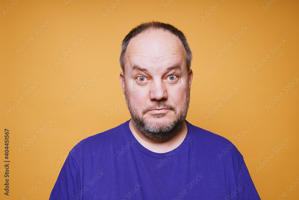 portrait of mid adult man with dumbfounded look on his face against orange color studio background - bewildered facial expression portrait of mid adult man with dumbfounded look on his face against orange color studio background - bewildered facial expression