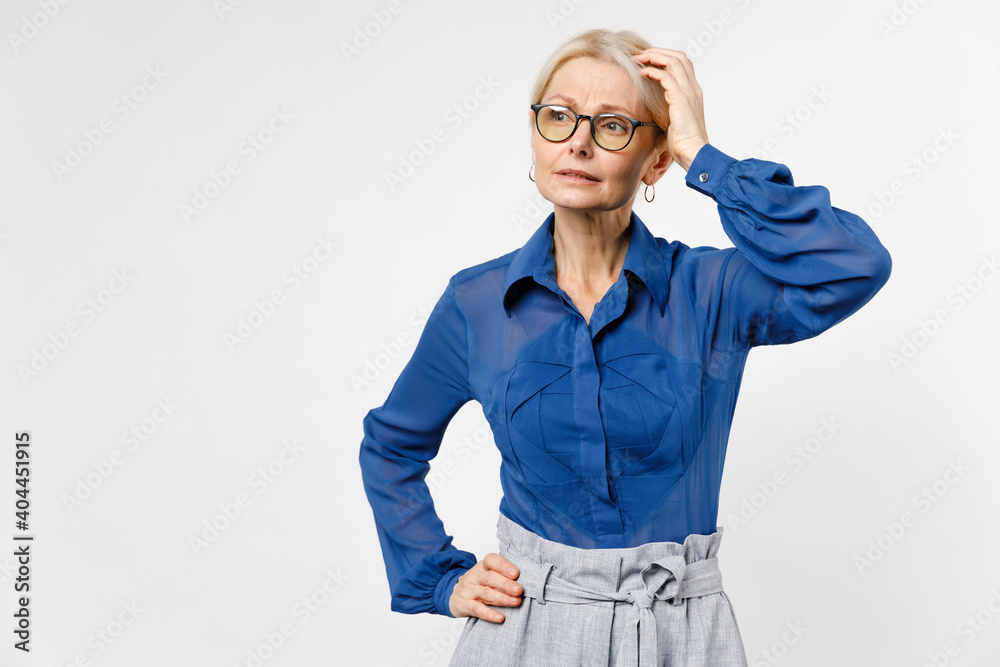 Blonde pensive thoughtful employee business woman 40s in blue classic shirt glasses formal clothes look aside making solution isolated on white background studio portrait. Achievement career concept. Blonde pensive thoughtful employee business woman 40s in blue classic shirt glasses formal clothes look aside making solution isolated on white background studio portrait. Achievement career concept.