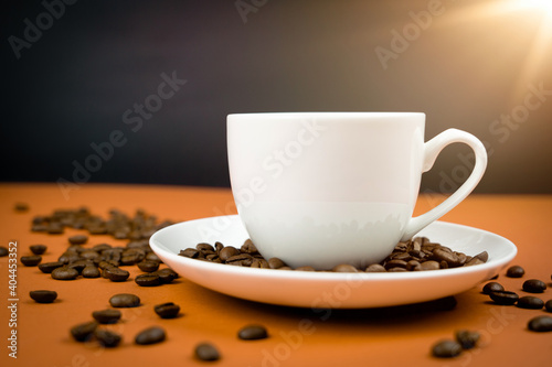 A cup of creamy coffee with roasted coffee beans