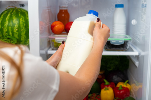 Female hand taking bottle of milk from a fridge