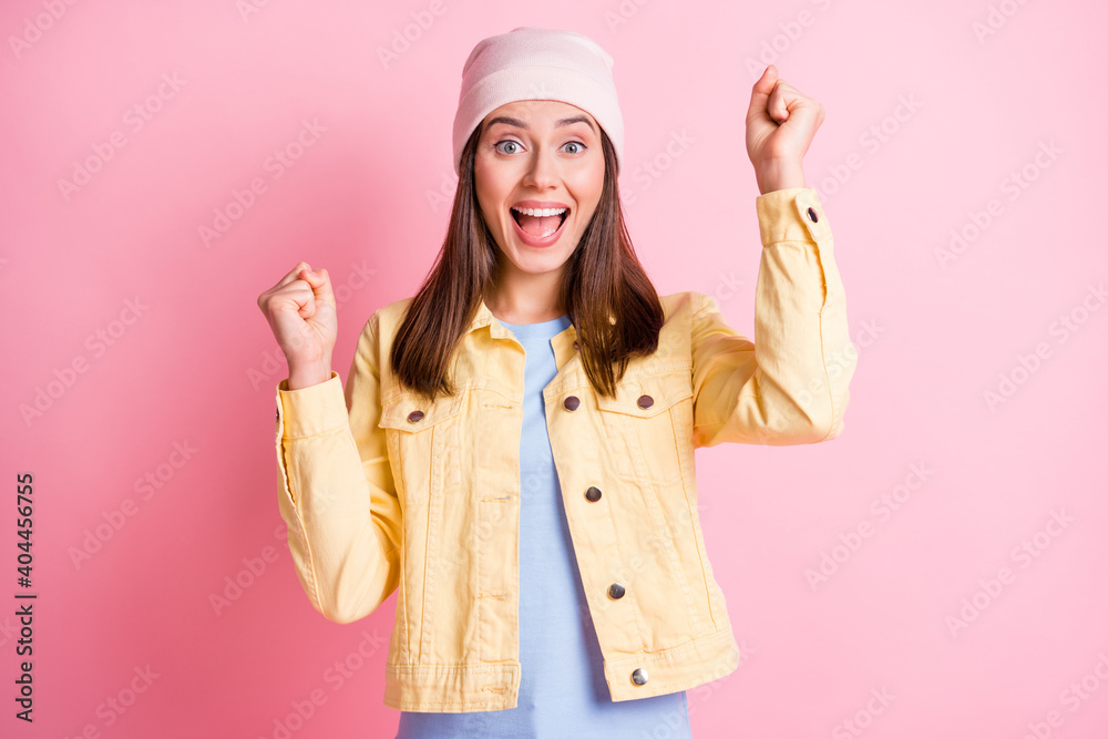 Photo of lucky charming young woman dressed casual clothes cap rising fists open mouth isolated pink color background Photo of lucky charming young woman dressed casual clothes cap rising fists open mouth isolated pink color background