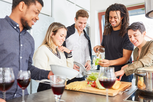 Lachende Freunde bereiten Salat vor f  r gemeinsame Mahlzeit in K  che