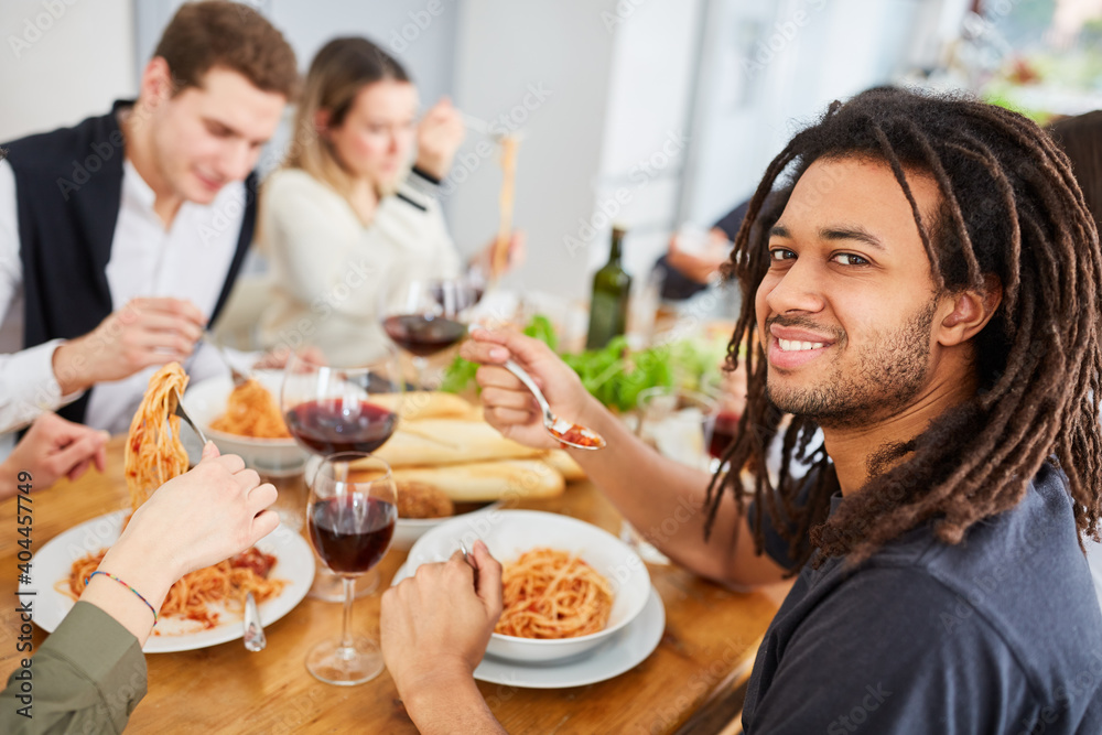 Mann mit Freunden beim gemeinsamen Pasta Essen in Küche einer WG