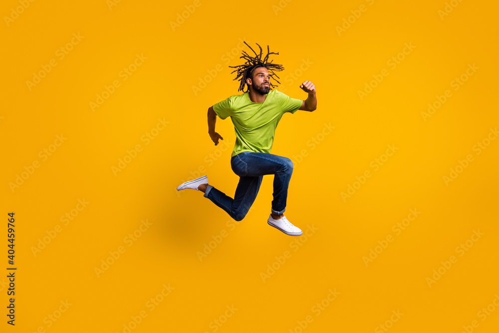 Photo portrait full body view of determined runner jumping up isolated on vivid yellow colored background