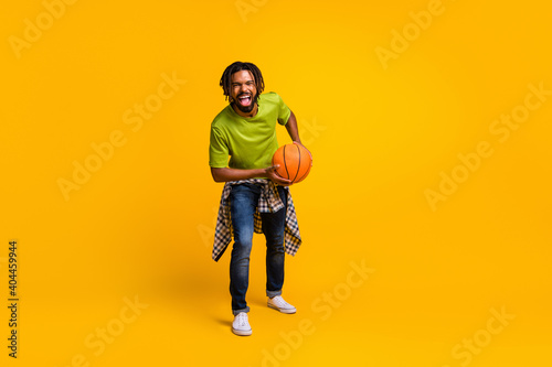 Photo portrait full body view of laughing guy holding ball isolated on vivid yellow colored background