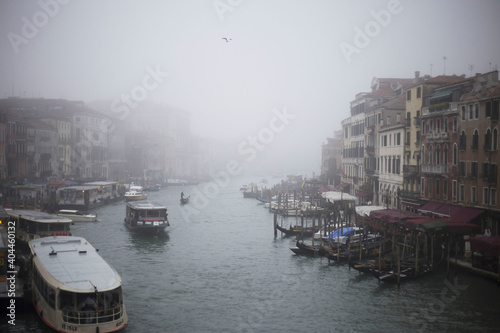 Venetian Grand Canal in a foggy winter day with boats and gondola
