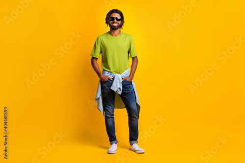 Full size photo of young handsome man happy positive smile hands in pocket summer travel wear denim isolated over yellow color background