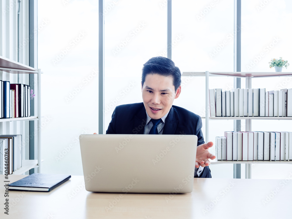 Fototapeta premium Asian handsome businessman in suit working with laptop computer on desk in office.