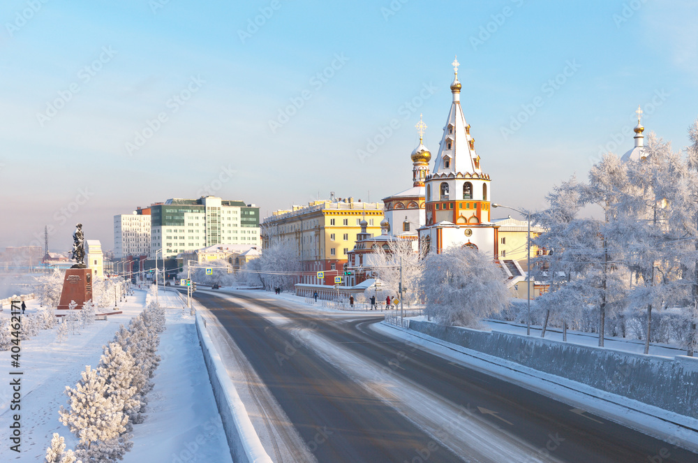 Siberian city of Irkutsk on a frosty winter day. View from the pedestrian bridge on the Lower Embankment of the Angara River to the beautiful Epiphany Cathedral - the architectural symbol of the city