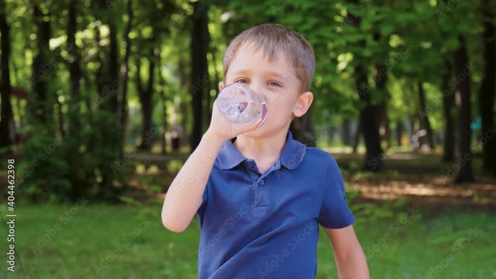 happy child resting in the park. The child drinks water from a bottle. The concept of healthy development of children and providing them with clean drinking water. happy child resting in the park. The child drinks water from a bottle. The concept of healthy development of children and providing them with clean drinking water.
