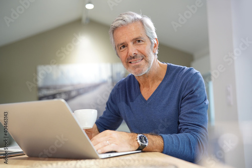 Portrait of senior man at home working on laptop