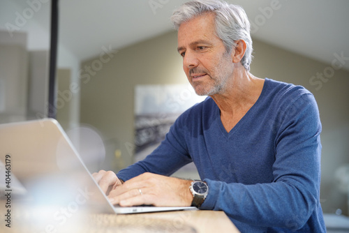 Portrait of senior man at home working on laptop