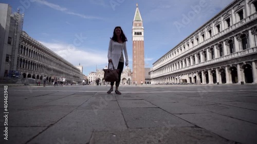 Attractive young woman walk on the square of Sanmarco in Venice Italy looking at the blue sky. photo