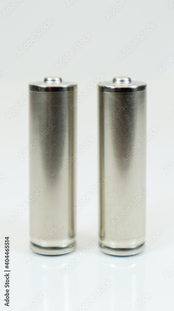 AA alkaline rechargeable batteries on white glossy background with reflection. Close up two empty batteries with copy space. Vertical photography. AA alkaline rechargeable batteries on white glossy background with reflection. Close up two empty batteries with copy space. Vertical photography.