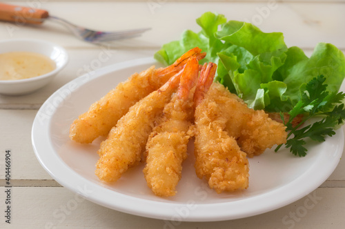Fried shrimps with green vegetable on plate and dip sauce .