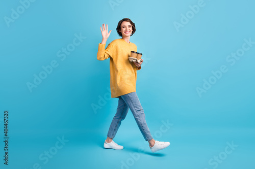 Full length body side profile photo of girl vawing with hand keeping drink holder with two hot coffee walking isolated on bright blue color background photo