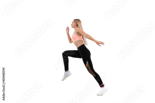 Sporty young woman in a pink top, leggings and sneakers runs forward