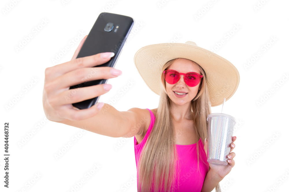Portrait of a young woman in a pink swimsuit and hat holding a glass and taking a selfie Portrait of a young woman in a pink swimsuit and hat holding a glass and taking a selfie