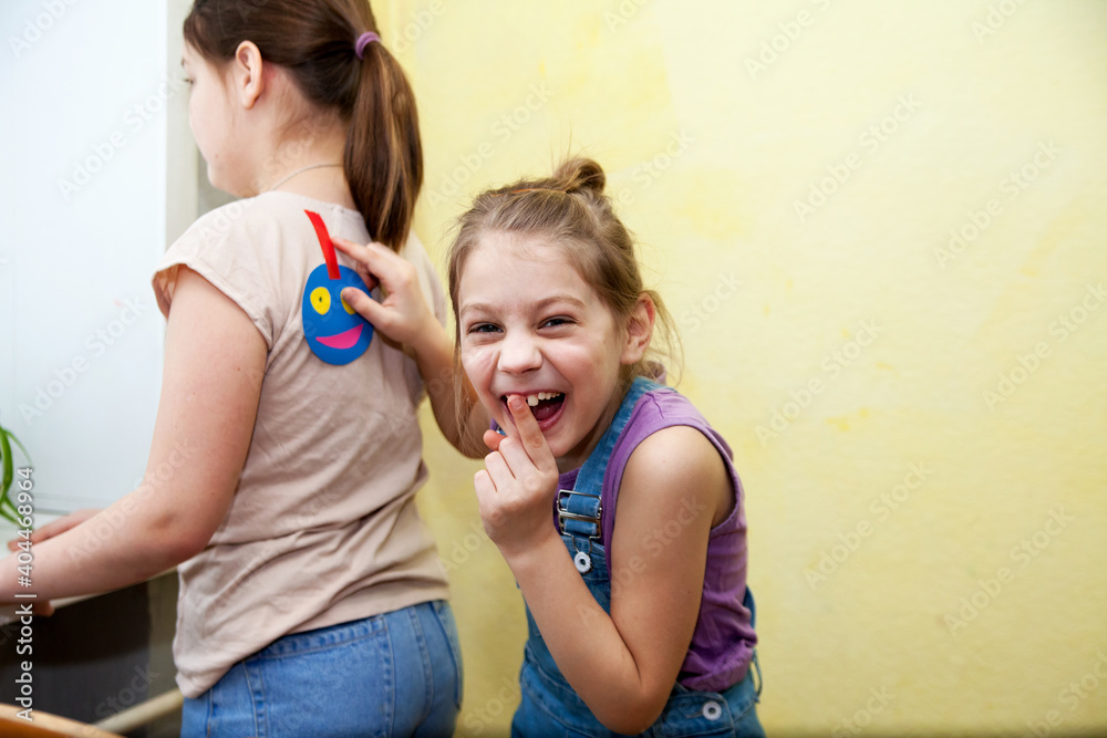 Ταπετσαρία Joke on  first of April,  girl sticking  smiley face on her girlfriend's back