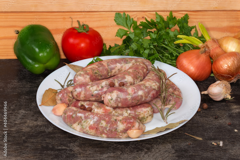 Uncooked homemade pork sausages semifinished on dish on black surface