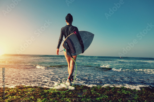 Photography Woman surfer with surfboard going to surf at seaside