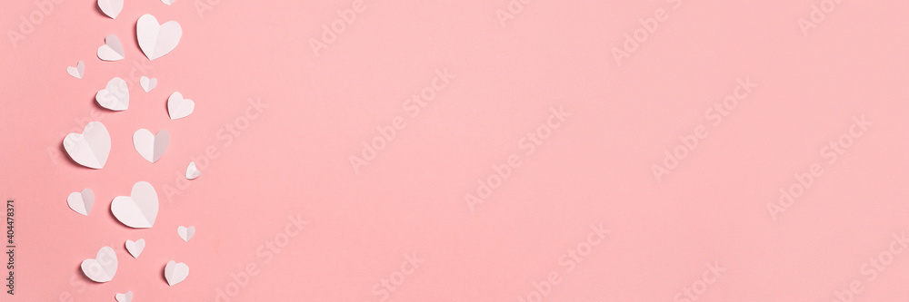 White hearts cut from paper on a pink background. Composition of Valentine's Day. Banner. Flat lay, top view