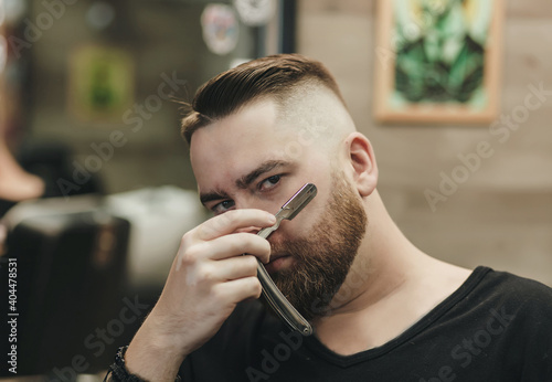 Sexy handsome bearded man holding a straight razor