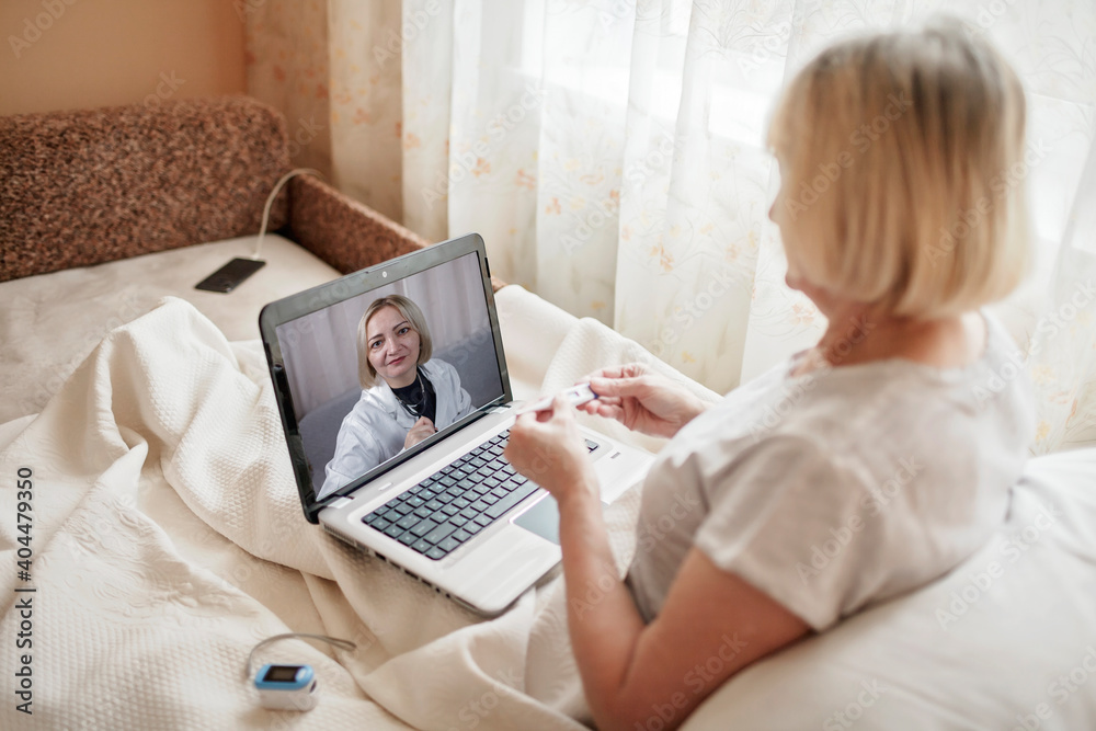 Old woman in bed looking at screen of laptop and consulting with a doctor online at home, telehealth services during lockdown, distant video call, modern tech healthcare application Old woman in bed looking at screen of laptop and consulting with a doctor online at home, telehealth services during lockdown, distant video call, modern tech healthcare application