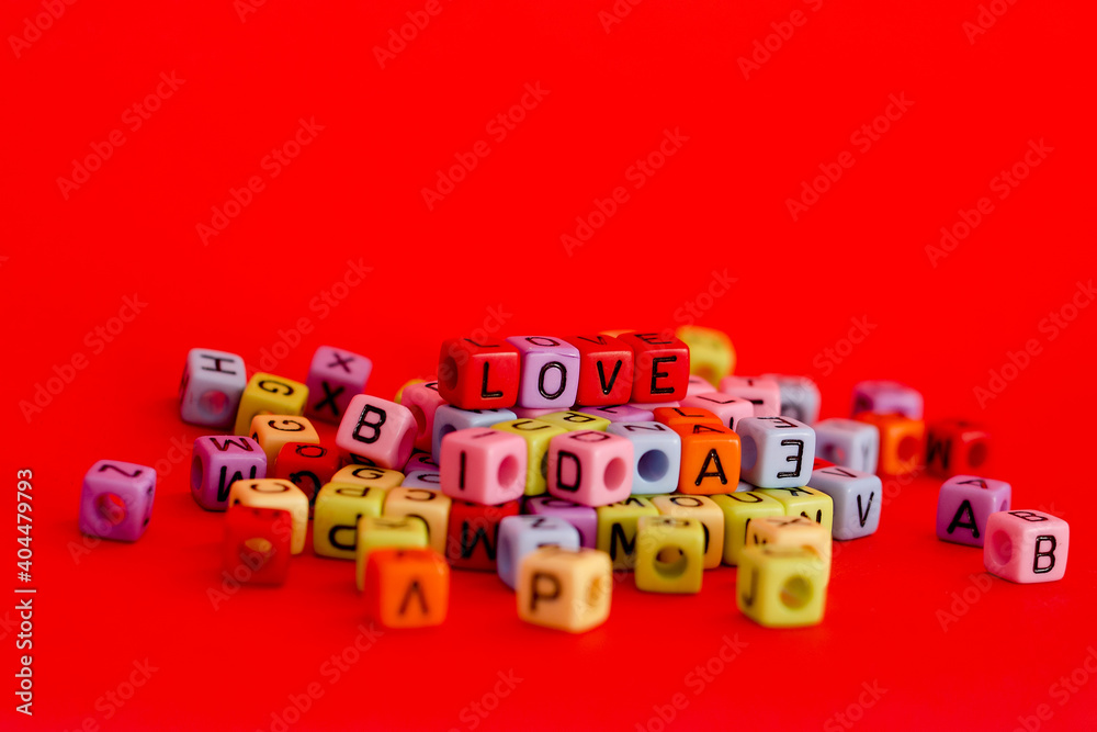 Obraz premium Colorful wooden cube beads with letters on red festive background, word