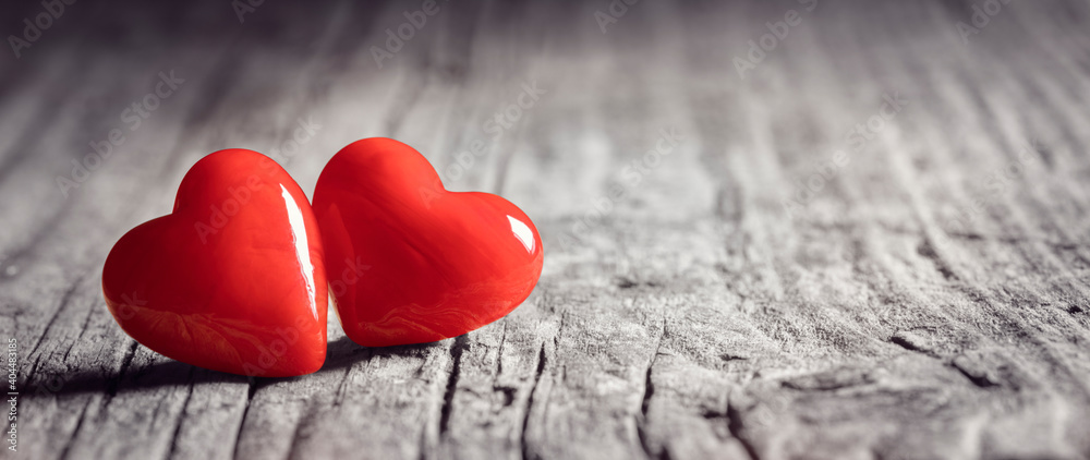 Obraz premium Two red hearts on a wood background concept for love, dating and romance with copy space