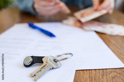 World leasing day. Realtor counts the money, in a blur. There are papers and keys on the table. Close up