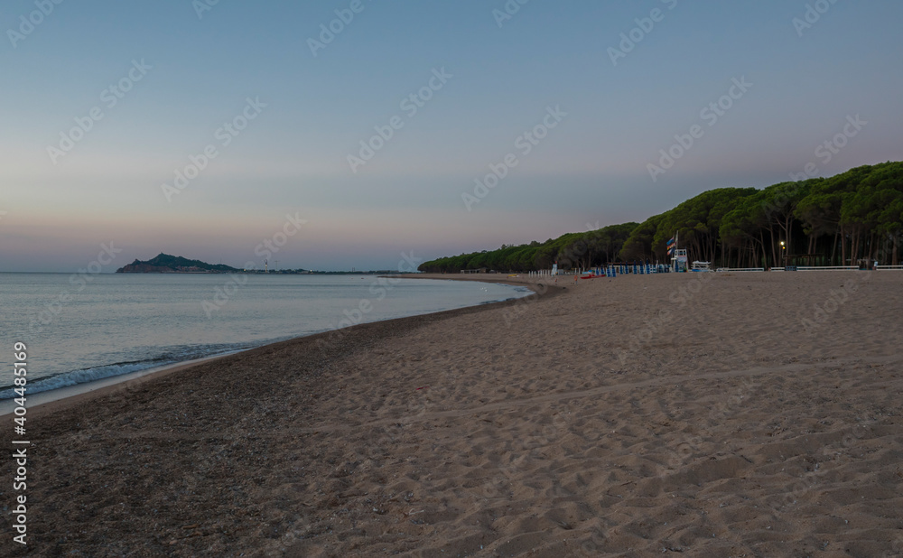 Early Morning Sunrise view of sand beach Spiaggia di Santa Maria Navarrese, sea with green forest and view of Arbatax penisula. Sardinia, Italy