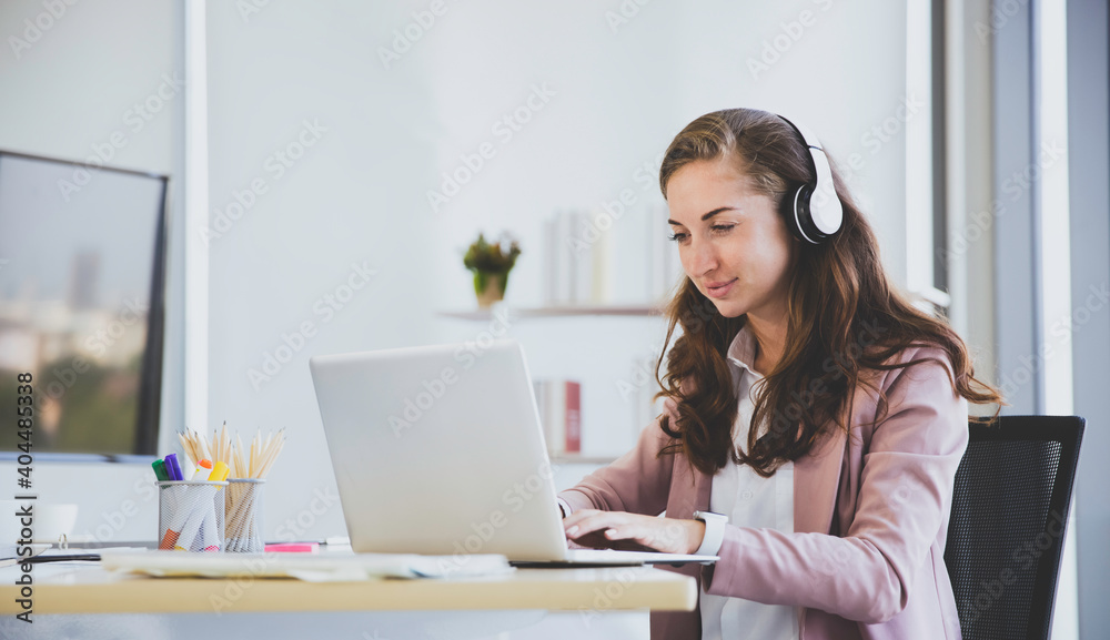 Concentrated Caucasian female in headphone working in modern office Concentrated Caucasian female in headphone working in modern office