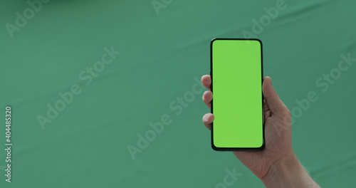 Man hand show phone with green screen over green background