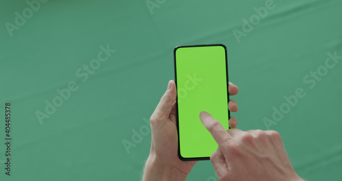 Man hand use phone with green screen over green background