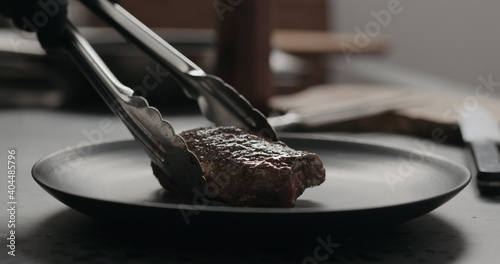 put whole beef steak on black plate on concrete countertop photo