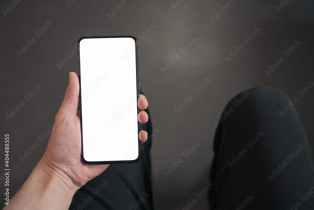 pov shot of man hand hold phone with white screen in dark interior