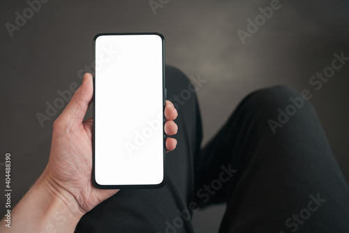 pov shot of man hand hold phone with white screen in dark interior photo