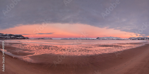 Wide panoramic view of winter sunset with amazing magenta color over fjord.