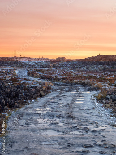An impassable icy road through the winter tundra. A rough, rocky road stretching away into the distance.