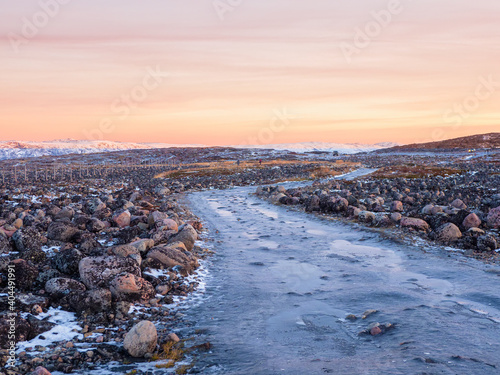 An impassable icy road through the winter tundra. A rough, rocky road stretching away into the distance.