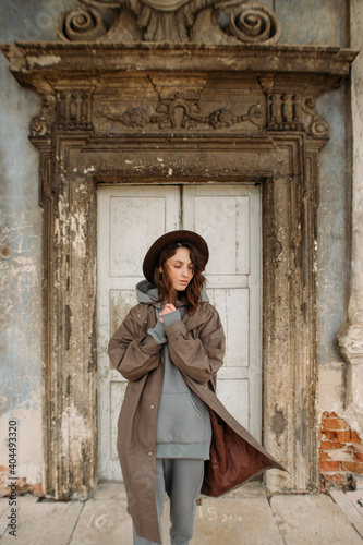 stylish young woman in a coat and hat in the old castle